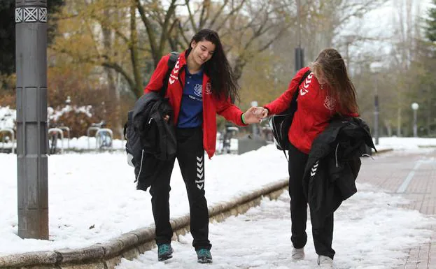 Dos jóvenes deportistas caminan con cuidado sobre restos de nieve helada por Vitoria. 