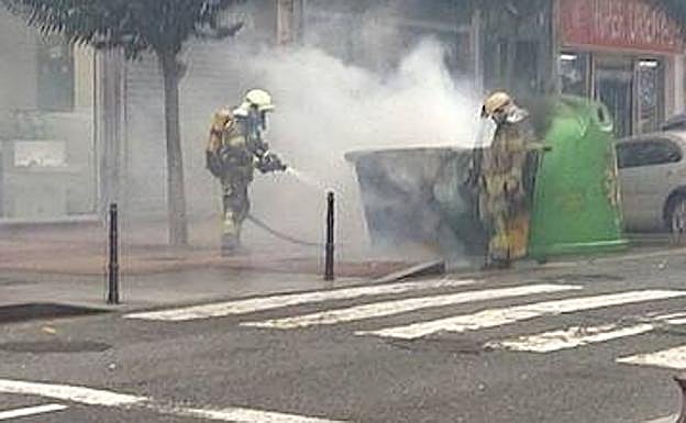 Bomberos extinguen las llamas de un contenedor en el centro de Barakaldo este domingo.