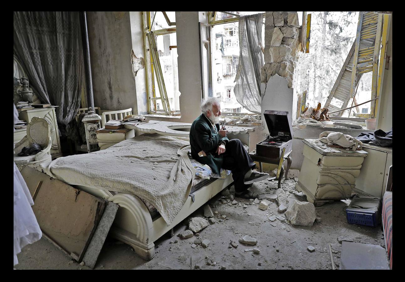 Marzo 2017. Mohamed Mohiedin Anís sentado en su dormitorio destrozado junto a su gramófono durante la guerra Siria.