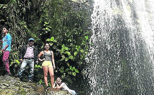 Imagen principal - Bilbaínos junto a la cascada de la cañada La Cristalina y, a la derecha, cafetales del pueblo.