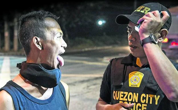 Control exhaustivo en Manila. Un agente de la Policía Nacional filipina inspecciona la boca de un sospechoso para comprobar si esconde droga en su interior. 