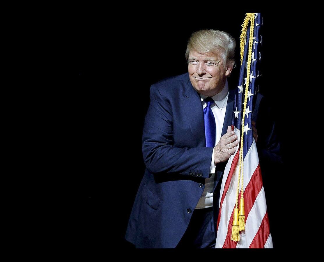 Donald Trump sujeta una bandera durante un acto de campaña en New Hampshire.