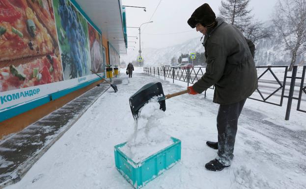 Un trabajador recoge nieve en una calle de una ciudad siberiana. 