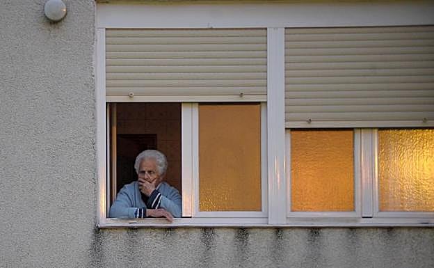 Una vecina, con rostro preocupado, en la ventana de su domicilio en Otxarkoaga. 
