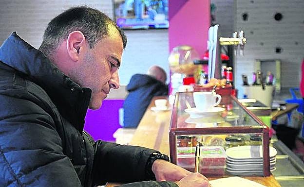 Un vecino firma la protesta en el bar de Pobes.