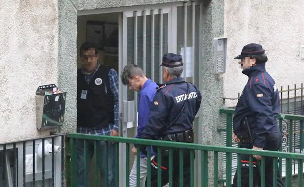 Agentes de la Ertzaintza acompañan al tercer detenido en el registro de su domicilio, en Otxarkoaga.
