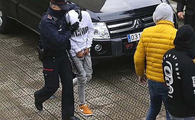 Un ertzaina conduce al segundo de los detenidos, de 14 años, al registro de su domicilio, en el barrio de Otxarkoaga.