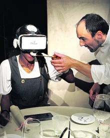 Imagen secundaria 2 - 1. Fernando Canales posa en su nuevo restaurante detrás de la vidriera que ha debido conservar. Los 500 metros del local de Ajuriaguerra ocupan el antiguo taller donde la familia Cañada realizaba vidrieras artísticas.2. Aspecto de la sala principal de la Despensa del Etxanobe. 3. Mikel Población ayuda a tomar un postre de violetas a una camarera con gafas de visión en 3D en los días previos a la apertura. Sobre estas líneas, el novedoso sistema que permite interactuar con los platos que se van a tomar mediante un dispositivo proyectado sobre el mantel.