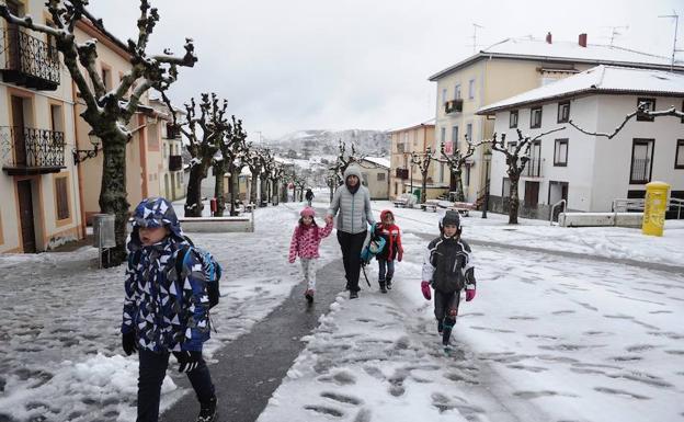 Niños acuden al colegio de La Arboleda que esta mañana ha amanecido cubierta de nieve.