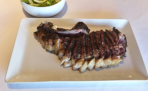 La chuleta del Txakoli Simón es una de las más demandadas de la capital vizcaína. De vaca frisona rubia gallega, está muy veteada. Óscar García y Borja Villanueva la conservan cinco semanas en la cámara antes de servirla al comensal. Filetean la carne para que se vaya atemperando y la pasan por la brasa de encina para caramelizar la parte exterior. El centro queda perfectamente rojo. Se sirve al cliente bastante limpia, sin hueso del costillar, y acompañada con una brasa individual para que el cliente se la acabe al gusto. 