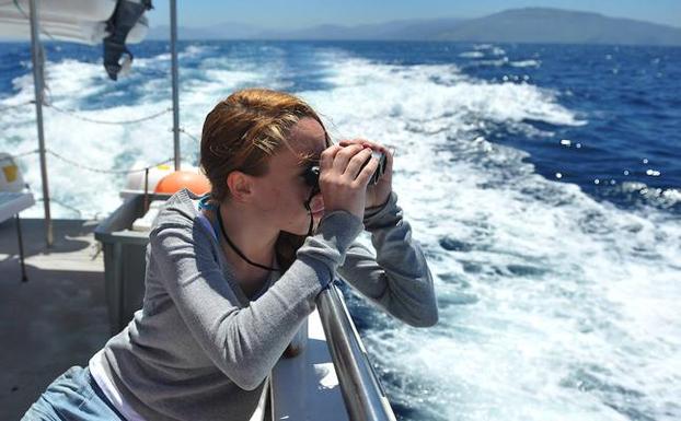 Una participante en las excursiones marinas busca con sus prismáticos algún cetáceo
