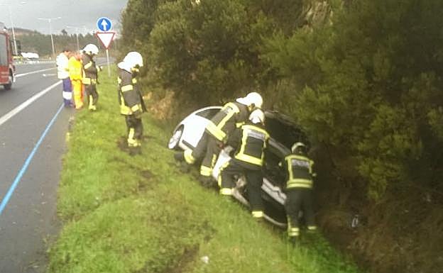 Los bomberos, con el coche accidentado.