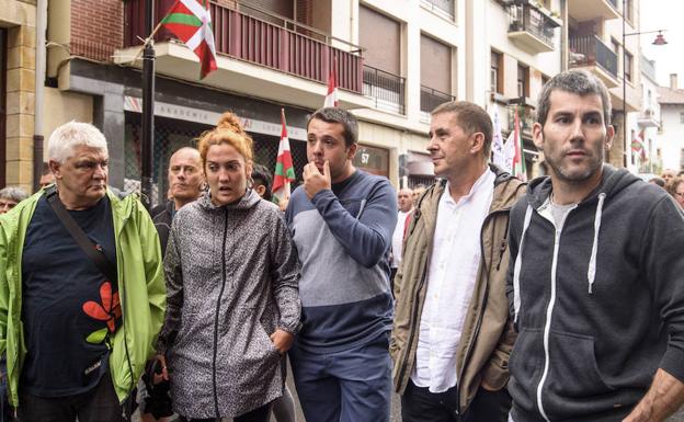 Imagen principal - Un acto de la izquierda abertzale a favor de los presos de ETA. Olatz Dañobeitia, recogiendo un cartel de Jarrai, y Miren Zabaleta.