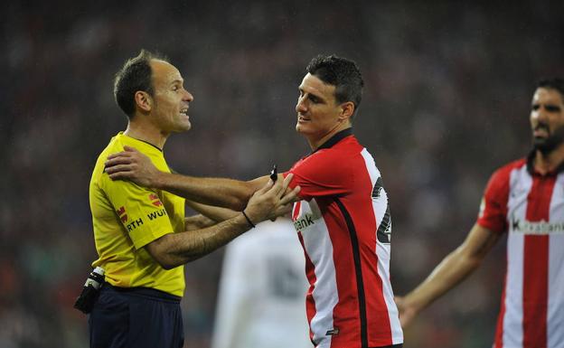 Mateu, uno de los árbitros más conocidos y polémicos, habla con Aduriz en un partido.