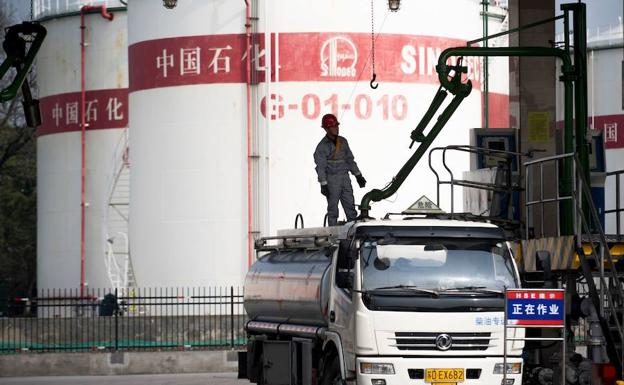 Un operario carga un camión cisterna en Shanghái.