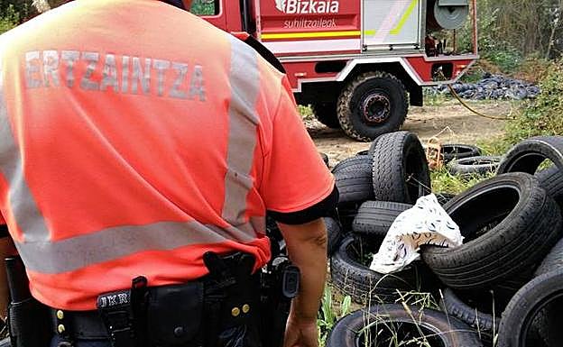 Un agente junto a varios neumáticos de un vertedero ilegal. 