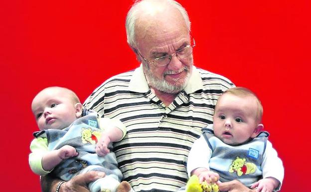 El australiano James Harrison, una leyenda nacional, posa con dos bebés en sus brazos.
