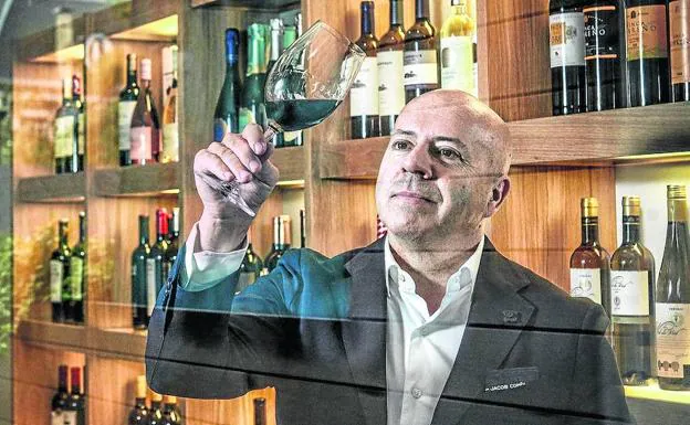 Ruiz de Galarreta analiza visualmente un tinto de Rioja Alavesa junto al botellero donde están representadas las diferentes bodegas de Araex.