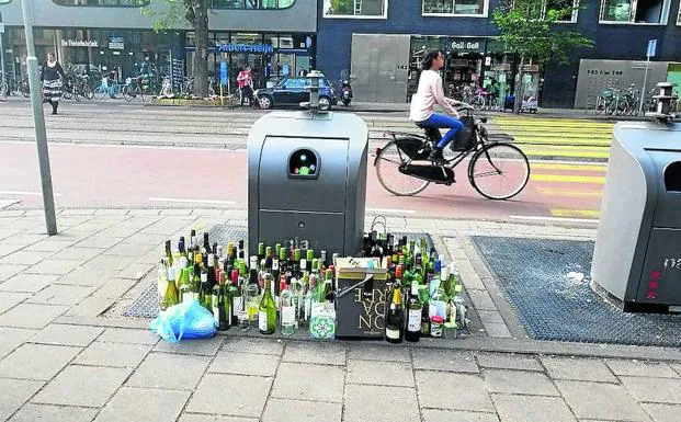 Botellas apiladas ante un contenedor de vidrio a rebosar en una calle holandesa. El país está a la cabeza del mundo en reciclaje.