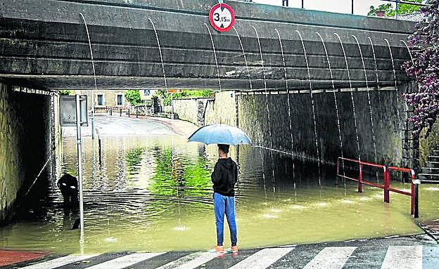 Imagen principal - 1. La calle Landako de Amurrio se inundó en unos minutos. 2. Un bombero trabaja en una lonja anegada en Amurrio. 3. El agua baja por Llodio.