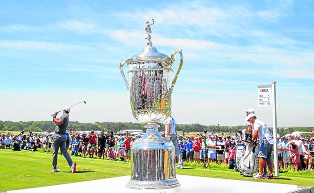 Koepka sale desde el tee del 1 junto al trofeo que acabaría conquistando por segundo año consecutivo.