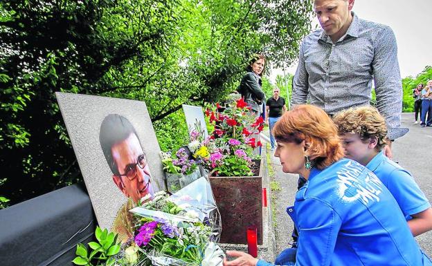 Josu Puelles, junto a un retrato de su hermano en el lugar en el que la explosión de una bomba acabó con su vida.