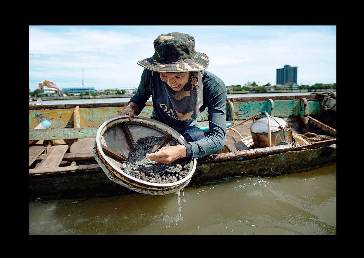 Hace unas semanas, equipos de buzos bien entrenados acapararon el interés mundial por el audaz rescate de 12 niños en una cueva anegada en Tailandia. Pero los buceadores de una pequeña comunidad de ese país, conocida como los «Indiana Jones,» se zambullen a diario hasta a 30 metros con un rudimentario casco de metal, que recuerda a una olla conectada a un tubo de goma, en el turbio cauce del río Chao Phraya, en Bangkok, en busca de tesoros. A veces, consiguen encontrar monedas, joyas o cerámica que pueden vender hasta por el doble del salario mínimo; otras, el hallazgo es macabro: cráneos y esqueletos sobre el lecho del río. Siempre a oscuras.