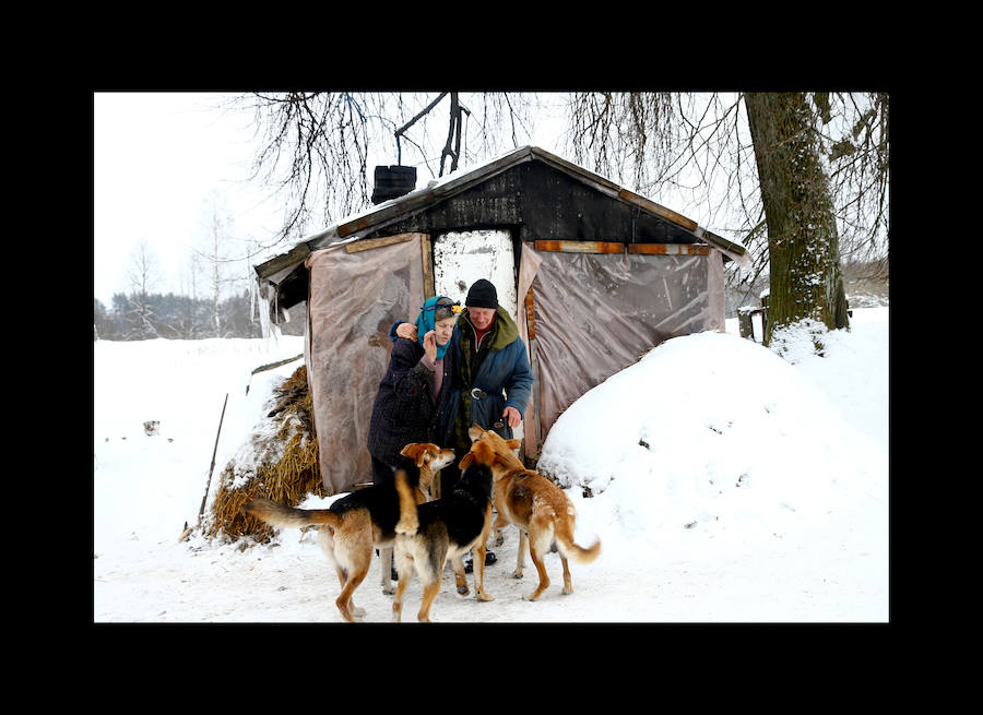 Yuri Baikov, de 69 años, hace un agujero para extraer agua del río congelado en su pequeña granja situada en un bosque cerca de la aldea de Yukhovichi, Bielorrusia, el 7 de febrero de 2018. Yuri y su esposa han vivido durante más de un cuarto de siglo en una choza primitiva en un bosque. Solían vivir en Yukhovichi, la aldea más cercana, como agricultores, criando vacas y aves de corral. Pero vivir cerca de otras personas no les sentaba bien. «No podemos dejar a nuestros animales y pájaros ni siquiera por un día, y no queremos»