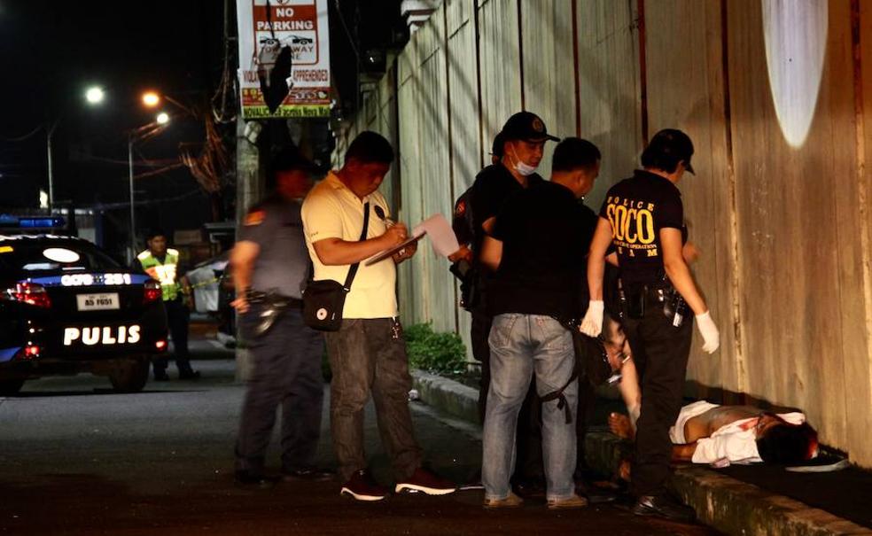 La Policía inspecciona el cadáver de un drogadicto abatido a tiros en Manila.