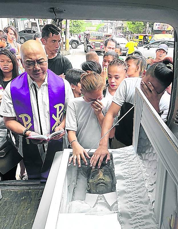 El padre Flavie Villanueva da su bendición a una de las víctimas.
