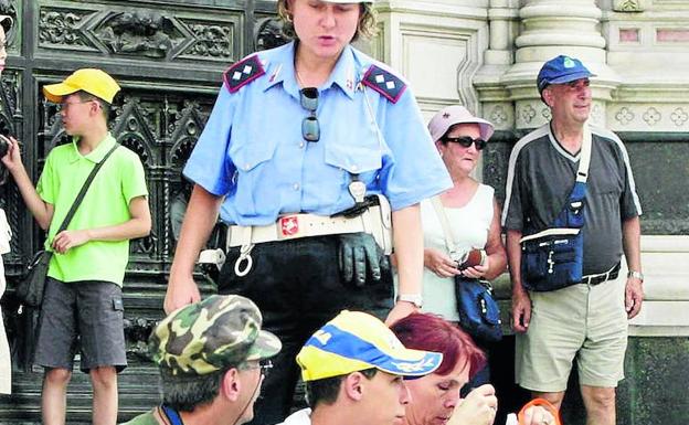 Una agente hace levantarse a unos turistas de las escalinatas. 