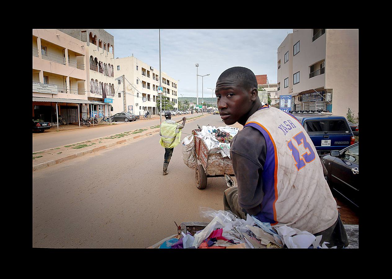 En Bamako, la capital de Mali, los carros tirados por jóvenes como Arouna Diabate (fumando un cigarrillo) y su hermano Salif (con camiseta del Real Madrid), tienen un importante papel en la lucha contra los desechos de la ciudad. Cada mañana, antes del amanecer, los Diabate sujetan el carro a su burro y comienzan las rondas de puerta en puerta para recoger la basura doméstica, que entregan en una estación local de residuos por un salario mensual de 35 dólares. Mali es uno de los países más pobres del mundo y las autoridades tratan de proporcionar servicios adecuados para combatir la proliferación de vertederos informales. La población de Bamako se cuadruplicó desde la década de 1970 hasta alcanzar casi 2 millones de habitantes en 2009.