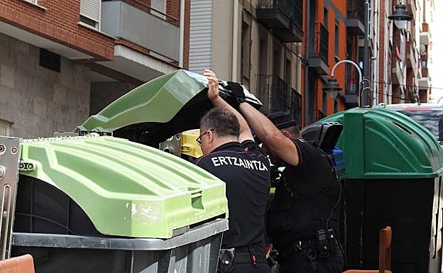 Agentes de la Ertzaintza buscan en los contenedores el arma homicida.