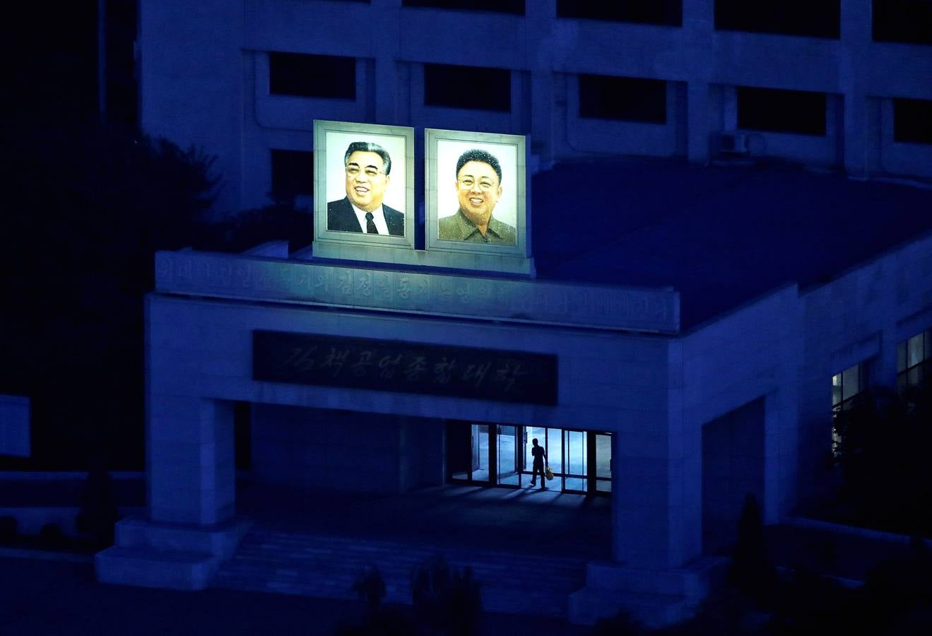 Una de las primeras cosas que uno ve cuando llega a Corea del Norte es un enorme retrato de Kim Il Sung a lo largo de la carretera del aeropuerto internacional de Pyongyang. Una imagen que muy pronto se vuelve omnipresente y hasta familiar. Millones de retratos, mosaicos y pinturas de Kim Il Sung, fundador del país, y su hijo Kim Jong Il, el padre del actual líder Kim Jong Un, recuerdan a la gente el papel central de la dinastía Kim. Sus imágenes son obligatorias no sólo en lugares públicos como estaciones de tren, hospitales, escuelas y fábricas, sino incluso en espacios privados como las salas de estar de los apartamentos. De día o de noche, allí donde vayas encontrarás su perturbadora sonrisa.