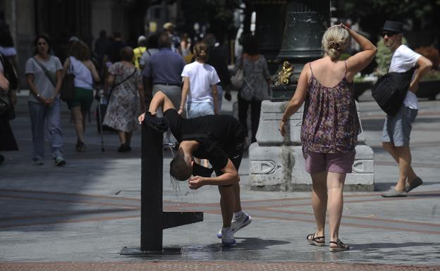 Un joven se refresca en un día de calor en Bilbao. 