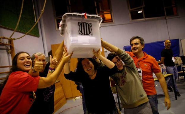 Voluntarios levantan una urna el 1 de octubre del año pasado al cierre de un colegio electoral.