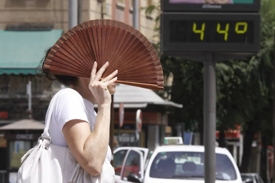 Una mujer se protege del sol con un abanico.