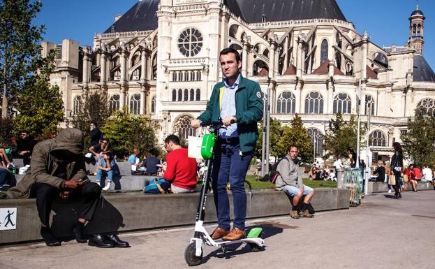 Un hombre circula en un patinete eléctrico, por la acera en una calle de París