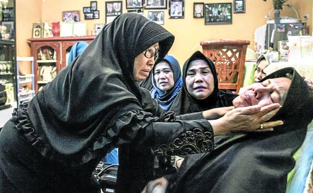 Una mujer es consolada por la pérdida de su esposo, que era uno de los pasajeros del avión indonesio siniestrado 