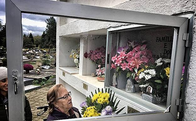 Una mujer coloca un ramo de flores en el camposanto de El Salvador.