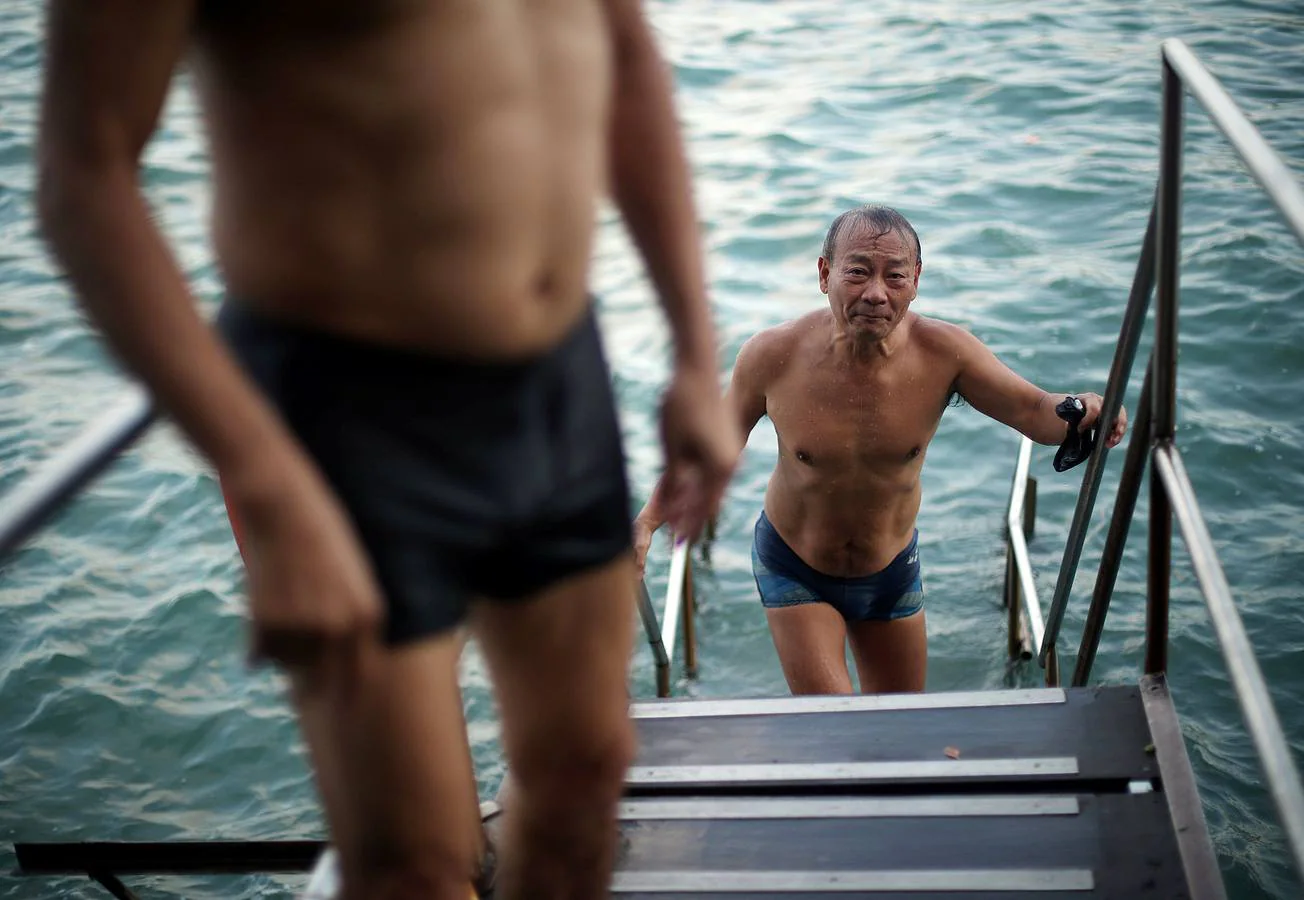 A Sandy Lam, de 68 años, le gusta zambullirse en las aguas del puerto de Hong Kong. Él (con una toalla blanca) y la mayor parte de los veteranos personajes que aparecen en las fotos llevan haciéndolo durante décadas frente al corazón financiero de la isla, rodeados de contenedores, ferris y barcos de pesca. A todos les une el deseo de mantenerse en forma. Su única queja es la contaminación: «Noto que hay más plástico en el mar. Es muy distinto a cuando nadaba aquí de pequeño. En el futuro será un problema.»