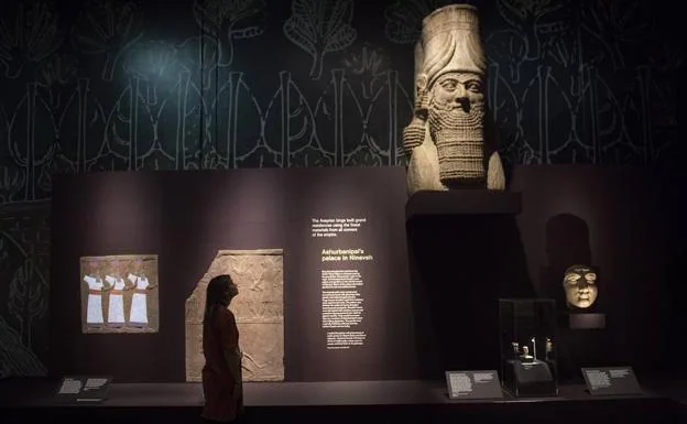 Una trabajadora del museo observa una estatua con cuerpo de toro, cabeza humana y alas de pájaro conocida como 'lamassu' durante la presentación a la prensa. 