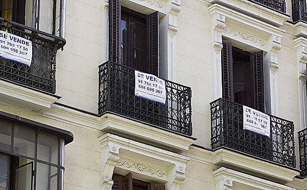 Un bloque de apartamentos en Madrid con carteles anunciando su venta.