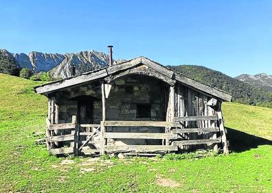 Imagen secundaria 1 - Un grupo de visitantes otea el cielo en busca de rapaces. Abajo, una cabaña de pastores y ganado en la braña.