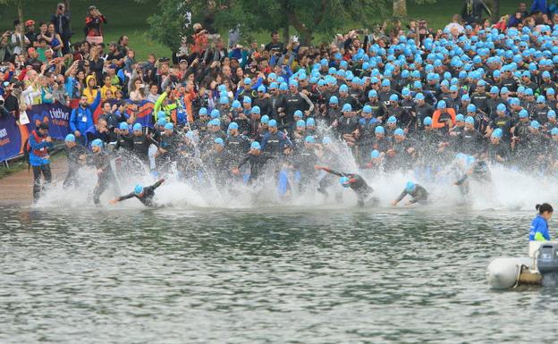 Una tropa de deportistas se zambulle en el agua del embalse de Ullíbarri-Gamboa para cubrir el sector a nado del Triathlon Vitoria-Gasteiz