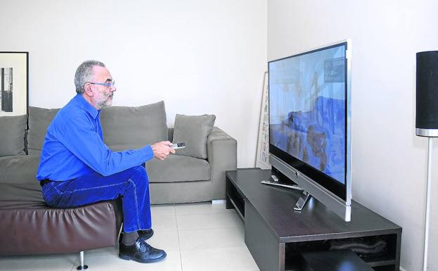 Un hombre de esa franja de edad maneja el mando a distancia frente al televisor.