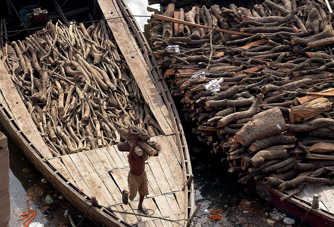 Todo hindú desea ser incinerado en Varanasi, la ciudad sagrada en el norte de la India. En sus ghats, a orillas del Ganges (en las fotografías vemos el ghat de Manikarnika), las piras funerarias son constantes y numerosos barcos cargados de madera la depositan con frecuencia. Cada una de las alrededor de 200 cremaciones que se realizan a diario necesita entre 200 y 400 kilos de madera, lo que significa que son consumidas hasta 80 toneladas. Un problema más para la polución en el país.