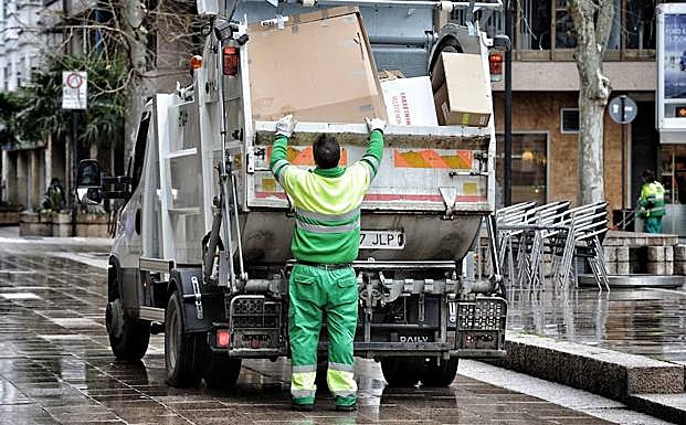 Un operario de la contrata de limpieza introduce cajas en un contenedor en una calle de Vitoria.