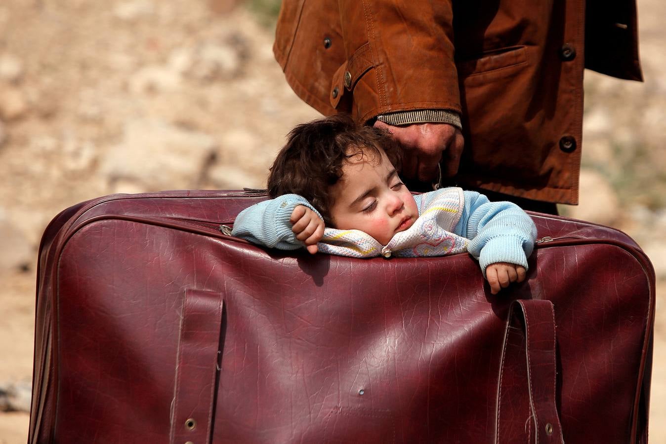 Un niño duerme en una bolsa en el pueblo de Beit Sawa, en el este de Ghouta, Siria