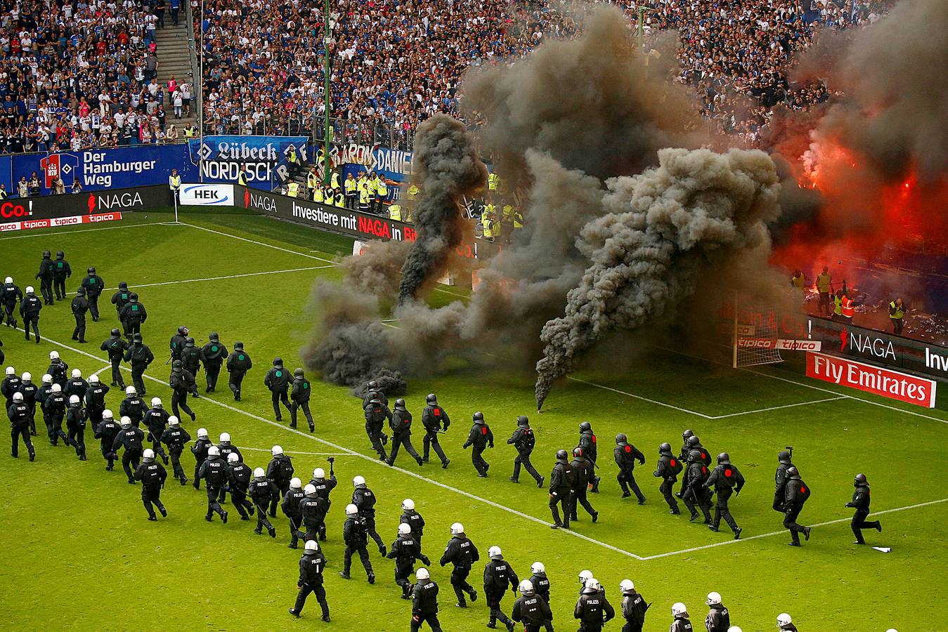 Los fanáticos del fútbol de Hamburgo lanzaron bengalas y bombas de humo al campo mientras la policía antidisturbios se alineaba en el campo durante un partido de la Bundesliga entre el Hamburger SV y el Borussia Moenchengladbach en el Volksparkstadion, Hamburgo, Alemania.